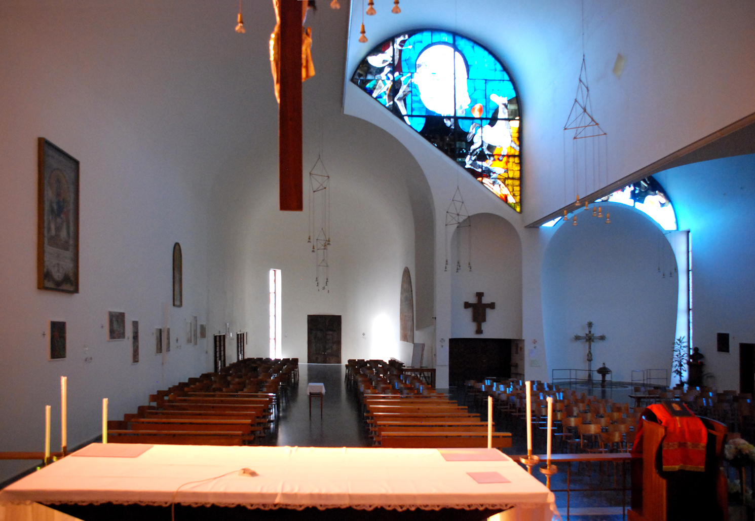 La vista dall'altare verso l'ingresso evidenzia il battistero a destra, sul retro dello spazio riservato alla cappella laterale. Una posizione defilata ma visibile e prossima all'ingresso.