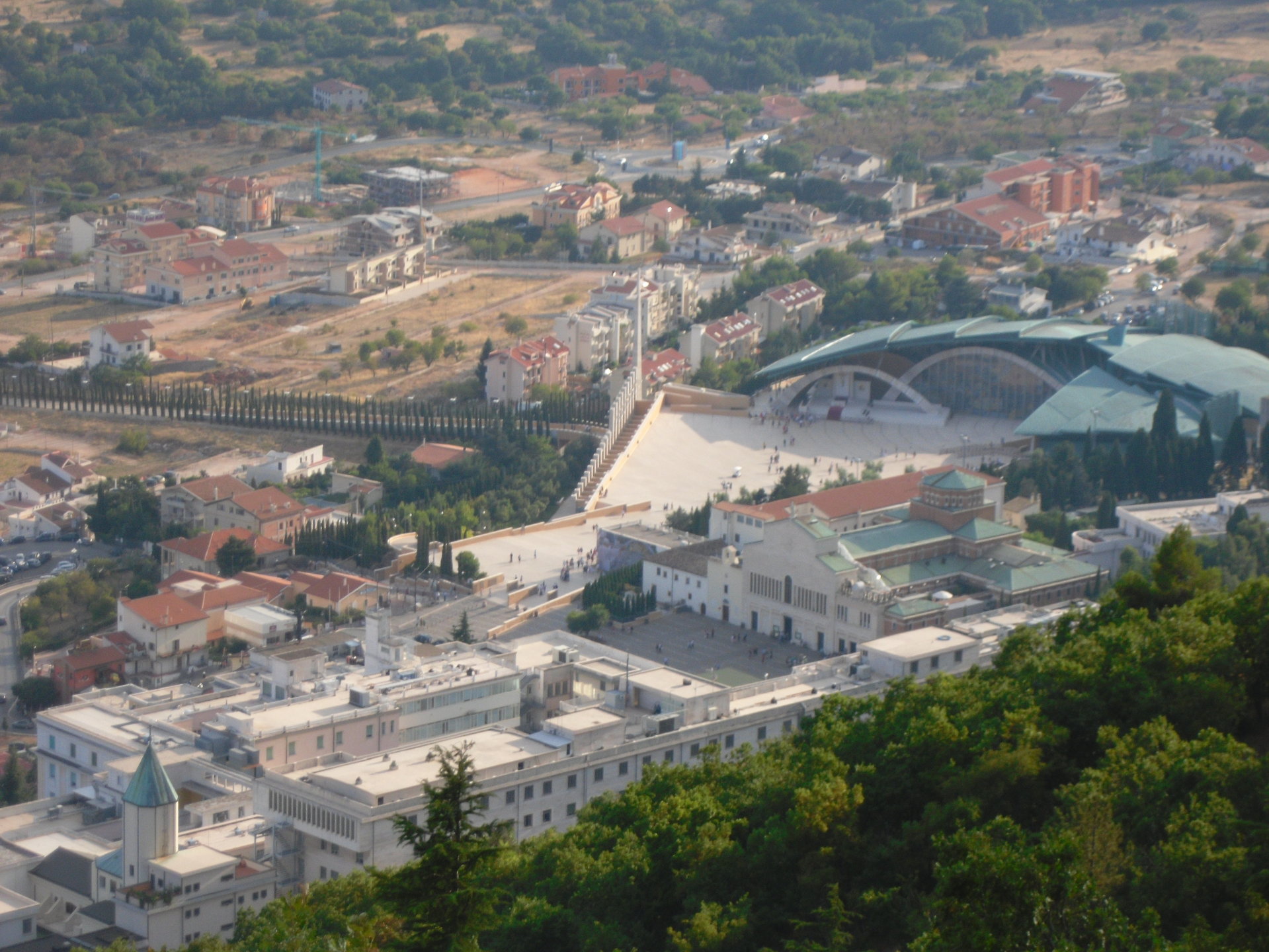 Vista aerea del complesso, col vasto sagrato antistante e gli archi della grande vetrata che vi prospettano.